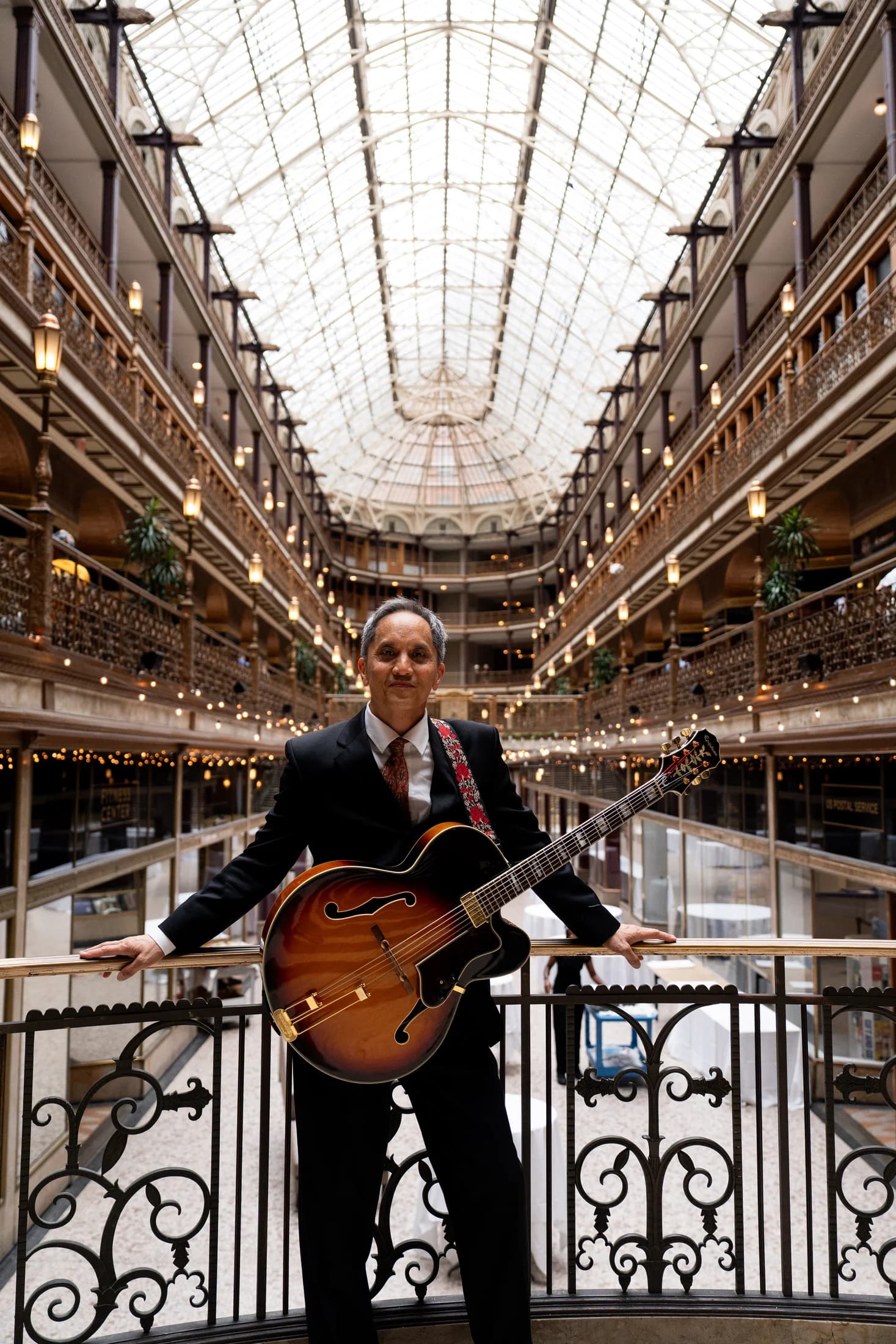 Gary Dacanay standing with a sunburst hollow-body guitar inside an ornate atrium.