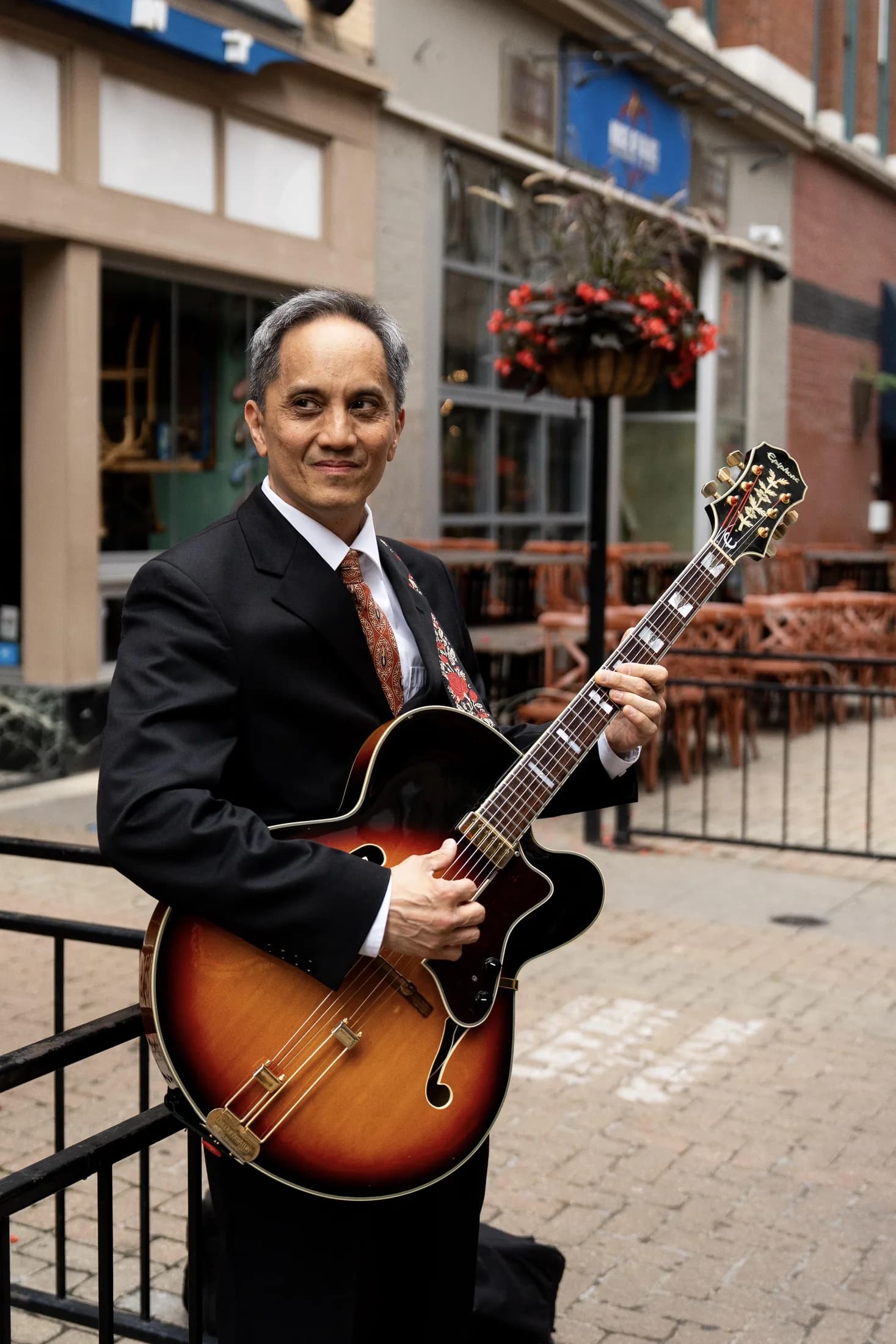 Gary Dacanay smiling with his guitar outside a downtown venue.